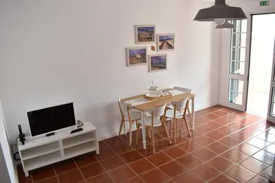 a dining room with a table and chairs and a television at Abrigo das Matas in Porto Santo
