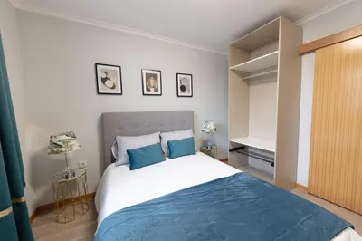a bedroom with a large bed with blue pillows at SWEET home I in Caniçal