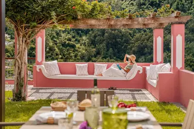 a woman sitting on a couch under a pergola at Casa do Rosário by An Island Apart in São Vicente