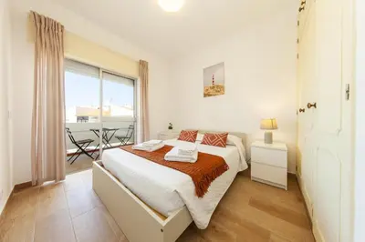 a white bedroom with a bed and a balcony at B69 - Village of Luz Apartment in Luz
