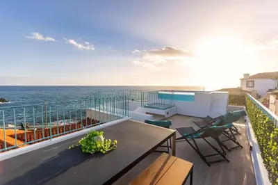 a balcony with a table and chairs and the ocean at Villa Belafonte in Câmara de Lobos