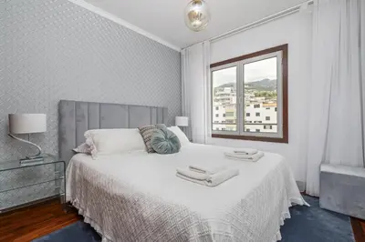 a white bedroom with a bed and a window at Fifth Apartment by Homie in Funchal