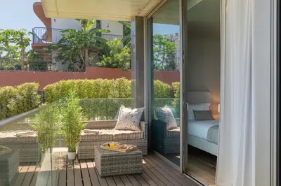 a balcony with a bed and chairs on a patio at Savoy Residence Casa Branca II by An Island Apart in Funchal
