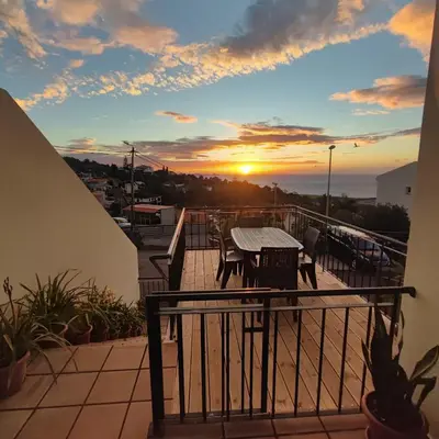a balcony with a table and chairs and a sunset at Villa&Damata in Machico