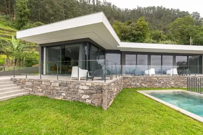 a house with a stone wall and a swimming pool at Villa Rocha in Arco da Calheta in Arco da Calheta