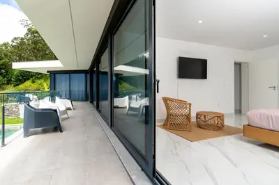 a house with glass walls and a patio with furniture at Villa Rocha in Arco da Calheta in Arco da Calheta