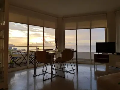 a living room with a table and chairs in front of windows at The Sunrise of your Dreams with Total Ocean View with New Modern Kitchens 75 m2 in Funchal
