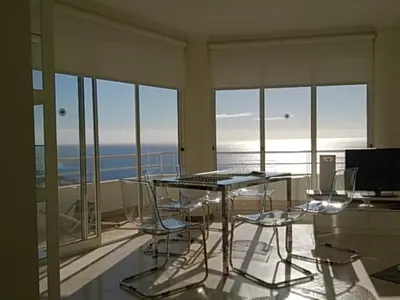 a dining table and chairs in a room with windows at The Sunrise of your Dreams with Total Ocean View with New Modern Kitchens 75 m2 in Funchal