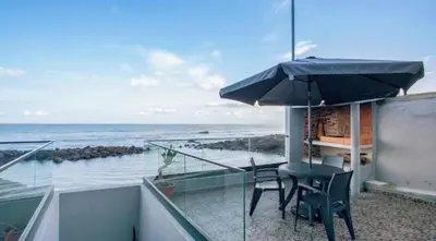 a balcony with a table and chairs and an umbrella at Casa dos avós in São Vicente