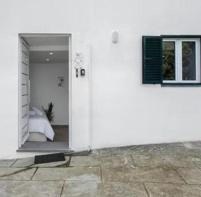 a white room with a bed and a window at Casa dos avós in São Vicente