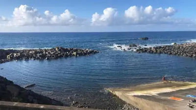 a large body of water with a bunch of rocks at Casa dos avós in São Vicente