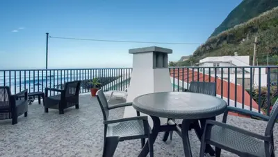 a table and chairs on a balcony with the ocean at Casa dos avós in São Vicente