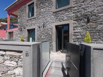 a stone house with a gate in front of it at Chalé Esmeralda - Charming Studios in Calheta Beach in Calheta
