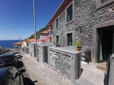 a stone building with cars parked on a street at Chalé Esmeralda - Charming Studios in Calheta Beach in Calheta