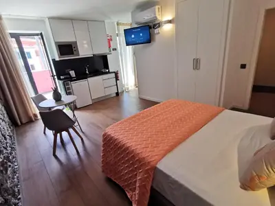 a bedroom with a bed and a table and a kitchen at Chalé Esmeralda - Charming Studios in Calheta Beach in Calheta