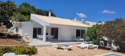 a white house with a patio with chairs and tables at Casa do Poço in Burgau