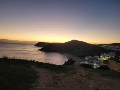 a view of a beach at sunset with a mountain at Casa do Poço in Burgau