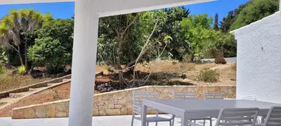 a patio with a table and chairs and trees at Casa do Poço in Burgau