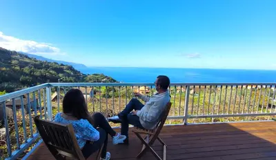 a man and a woman sitting on chairs on a deck at Faria's House in Ponta Delgada