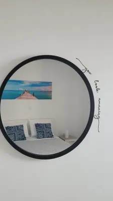 a round mirror in a white room with a bed at Faria's House in Ponta Delgada