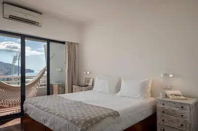 a white bedroom with a bed and a balcony at Vista Mar I by An Island Apart in Funchal