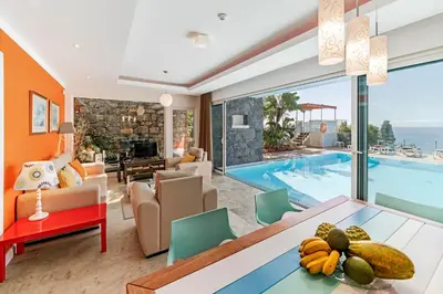 a living room with a dining table and a swimming pool at Beautiful Calheta Villa Villa Do Mar Iii 3 Bedrooms Infinity Pool in Arco da Calheta
