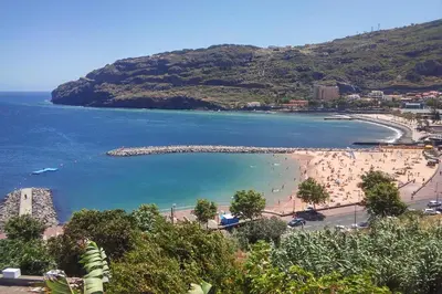 a view of a beach with people in the water at Sunny Beach Machico Apartment by Holiday Rental Madeira in Machico