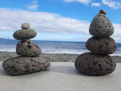 a stack of rocks sitting on the beach at Sunny Beach Machico Apartment by Holiday Rental Madeira in Machico