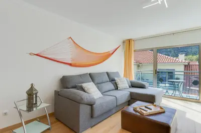 a living room with a couch and a hammock on the wall at Sunny Beach Machico Apartment by Holiday Rental Madeira in Machico