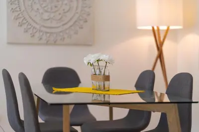 a dining room table with chairs and a vase of flowers at Sunny Beach Machico Apartment by Holiday Rental Madeira in Machico
