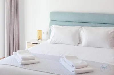 a white bed with two towels on top of it at MC Suites Burgau with amazing front sea view in Burgau