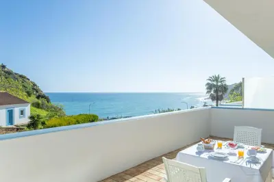 a balcony with a table and a view of the ocean at MC Suites Burgau with amazing front sea view in Burgau