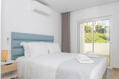 a white bedroom with a bed with two towels on it at MC Suites Burgau with amazing front sea view in Burgau
