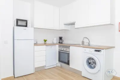 a white kitchen with a washer and dryer at MC Suites Burgau with amazing front sea view in Burgau