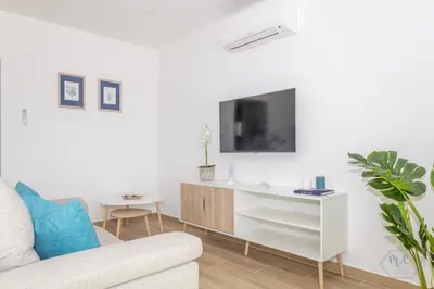 a living room with a couch and a tv on a wall at MC Suites Burgau with amazing front sea view in Burgau