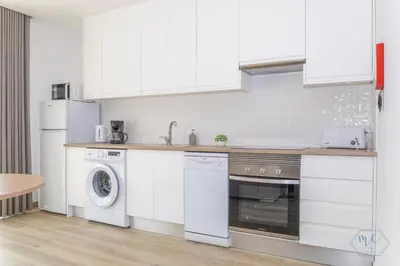 a kitchen with white cabinets and a washer and dryer at MC Suites Burgau with amazing front sea view in Burgau