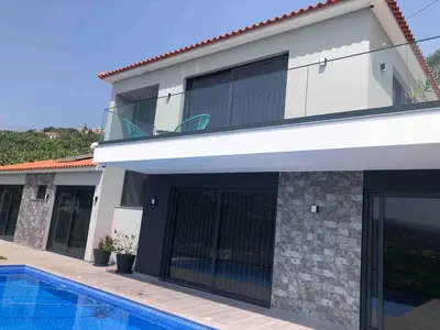 a house with a swimming pool in front of it at Villa Sol e Mar in Ribeira Brava