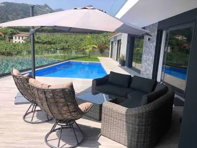 a patio with chairs and an umbrella next to a pool at Villa Sol e Mar in Ribeira Brava