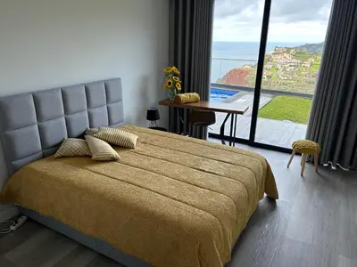 a bedroom with a bed and a table with a view at Villa Sol e Mar in Ribeira Brava