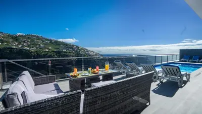 a balcony with chairs and a table and a pool at Villa Oceânica by LovelyStay in Ribeira Brava