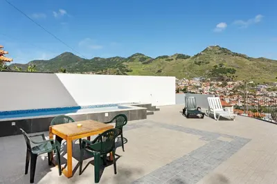 a patio with a table and chairs on a roof at Casa da Pontinha in Machico