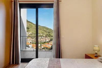 a bedroom with a bed and a balcony at Casa da Pontinha in Machico