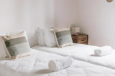 a bedroom with two beds with white sheets and pillows at Casa Nook Arrifana in Aljezur