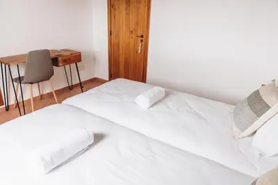 a white bed in a room with a desk at Casa Nook Arrifana in Aljezur