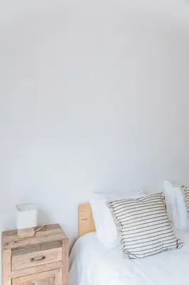 a bedroom with white walls and a bed with a nightstand at Casa Nook Arrifana in Aljezur