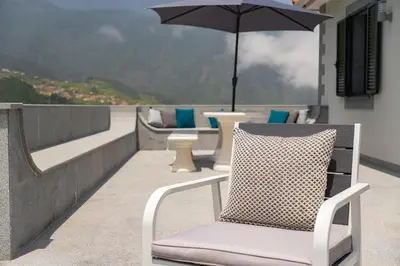 a chair sitting on a balcony with an umbrella at Casa Avô da Pedra, By OP in São Vicente