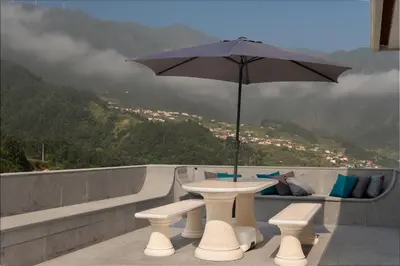 a table with an umbrella on top of a mountain at Casa Avô da Pedra, By OP in São Vicente