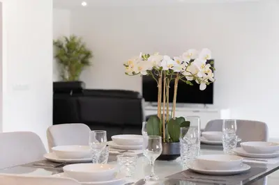 a table with plates and glasses and a vase of flowers at Casa Avô da Pedra, By OP in São Vicente