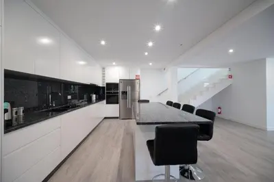 a kitchen with white cabinets and a counter with chairs at Casa Avô da Pedra, By OP in São Vicente