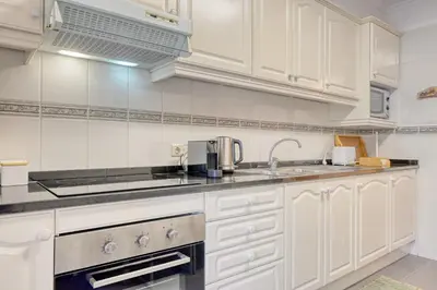 a kitchen with white cabinets and a sink at Costa do Sol, a Home in Madeira in Funchal